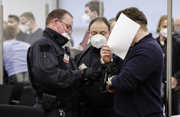 The defendant Rabieh R., right, hides his face as he is led into a courtroom of the Higher Regional Court in Dresden, eastern Germany on January 28, 2022 prior to the start of a trial over a jewellery ...