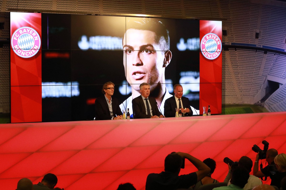 Neuer Trainer Carlo Ancelotti, Vorstands-Vorsitzender Karl-Heinz Rummenigge, Pressesprecher Dieter Nicklas bei der PK. Im Hintegrund l�uft ein Interview mit seinem Ex-Spieler Christiano Ronaldo / Fuss ...