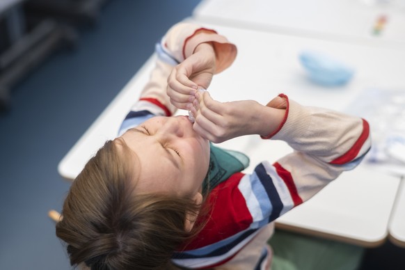 Eine Schuelerin beim Spucktest (PCR-Speichel-Test) in einem Schulzimmer der Schule Pfingstweid in Zuerich, aufgenommen am Dienstag, 11. Januar 2022. Mit regelmaessigen Tests an Schulen versuchen die B ...