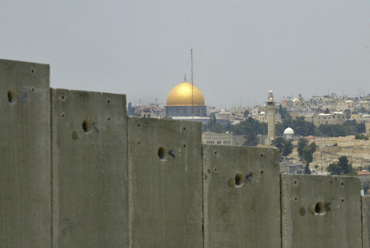 FILE - This July 9, 2004 file photo shows the golden shrine of the Dome of the Rock in Jerusalem's Old city can be seen behind a section made of concrete walls of the controversial separation bar ...