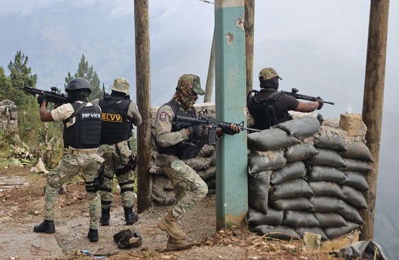 epaselect epa12283711 Members of the Haitian National Police (PNH) fire their weapons after an attack by an armed gang in Kenscoff, Haiti, 04 August 2025. At least eight people, including a three-year ...