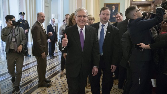 epa06465838 Senate Majority Leader Mitch McConnell (C) gives the thumbs up as he walks off the Senate floor after a successful cloture vote that opens the door for final passage later in the day in th ...