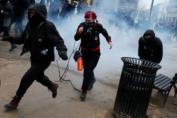 Activists run after being hit by a stun grenade while protesting against U.S. President Donald Trump on the sidelines of the inauguration in Washington, DC, U.S., January 20, 2017. REUTERS/Adrees Lati ...