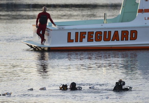 FILE - In this April 9, 2015, file photo, divers emerge from the water as debris believed to be from a car floats to the surface where a car went off a pier and into the water in Los Angeles' San Pedr ...