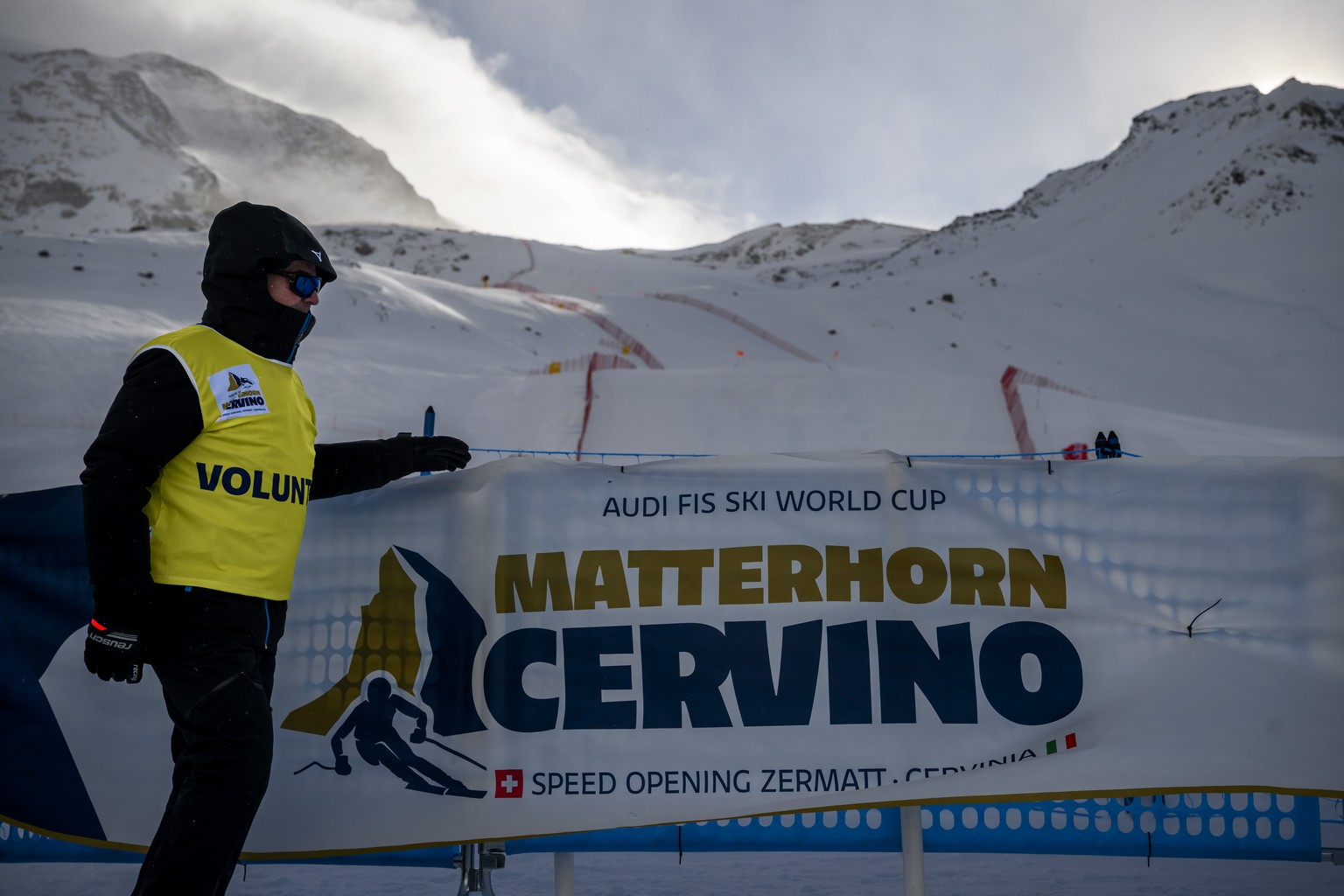 A volunteer walks through the finish area in a strong wind during the women&#039;s downhill race on the new ski course &quot;Gran Becca&quot; at the Alpine Skiing FIS Ski World Cup Zermatt-Cervinia, i ...