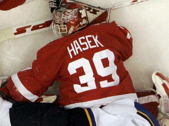 Detroit Red Wings goalie Dominik Hasek, of the Czech Republic, searches for the puck as St. Louis Blues defenseman Eric Brewer (4) lands on him during the third period of Detroit&#039;s 5-3 win in an  ...