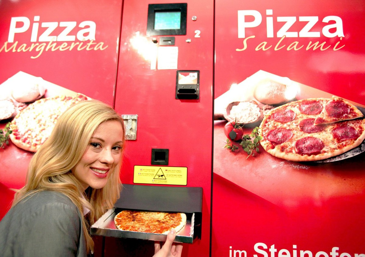 epa02903979 A model takes a pizza out of a vending machine produced by 'Pizzomatic' in Cologne, Germany, on 08 September 2011. From 08 to 10 September 2011 'Eu'Vend' fair for  ...