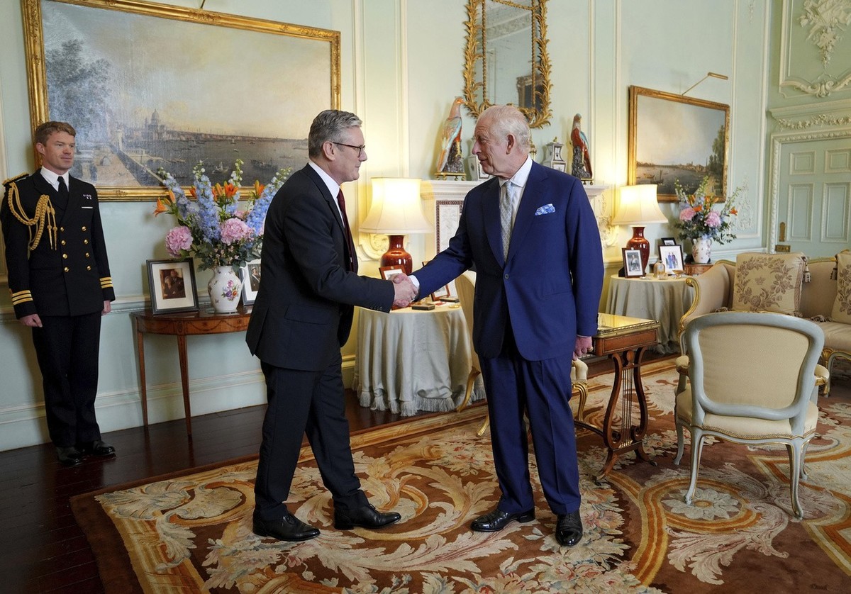 Britain's King Charles III, right, shakes hands with Keir Starmer where he invited the Labour Party leader to become prime minister and to form a new government, following the landslide general e ...