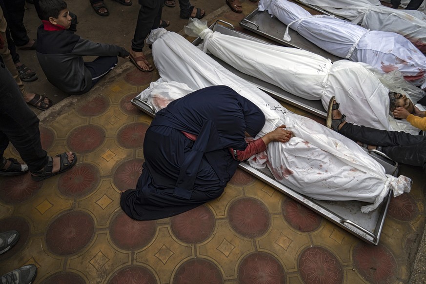 A woman mourns the covered bodies of her child and husband killed in an Israeli army bombardment of the Gaza Strip, at the hospital in Khan Younis, Tuesday, December 1.  5, 2023. (AP Photo/Fatima Shbair)