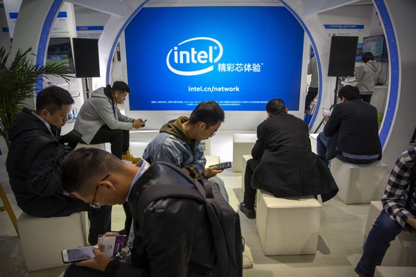 Attendees look at their smartphones at a booth from chipmaker Intel at the PT Expo in Beijing on Oct. 31, 2019. Intel Corp. apologized Thursday, Dec. 23, 2021 for asking suppliers to avoid sourcing go ...