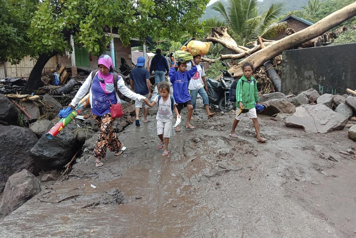 Des gens marchent au milieu des débris dans un village touché par les inondations à Ile Ape, sur l'île de Lembata, dans la province de Nusa Tenggara Est, en Indonésie, dimanche 4 avril 2021. Wats ...
