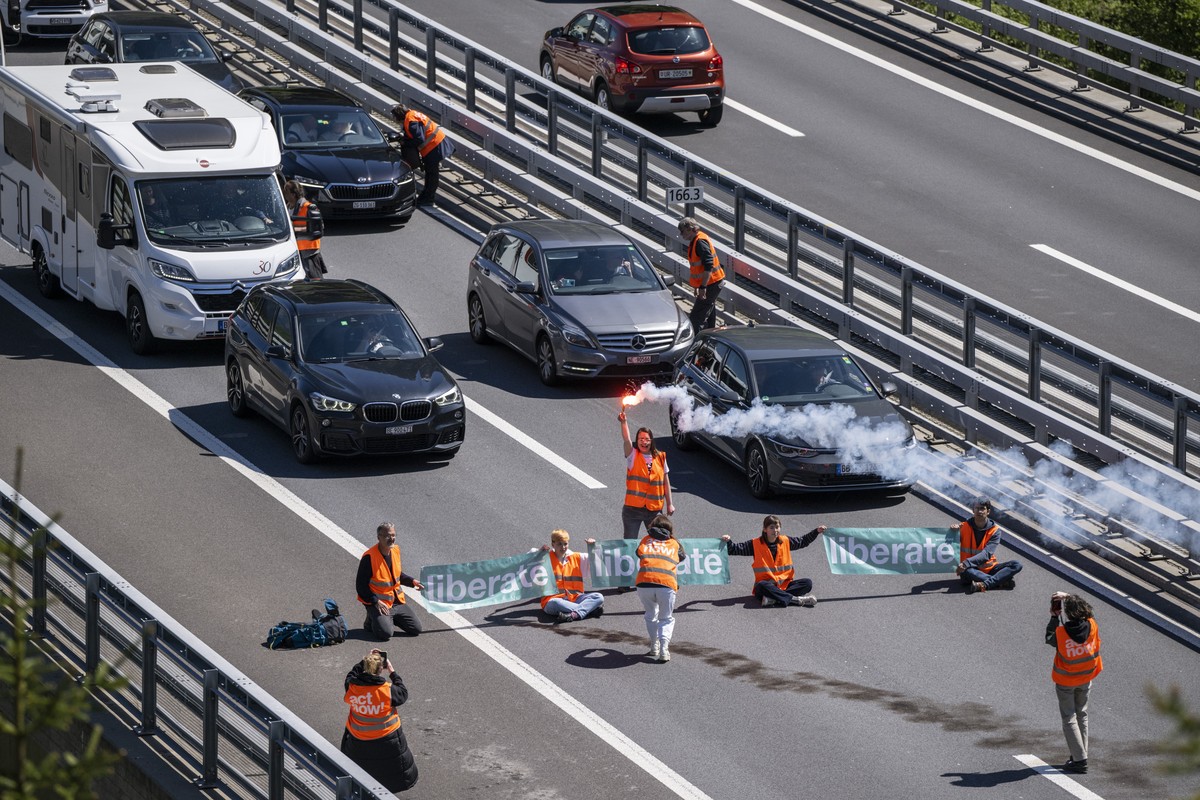 Aktivisten von "Renovate Switzerland" protestieren vor dem Gotthard Tunnel bei Goeschenen im Kanton Uri, weahrend dem sich der Auffahrt Reiseverkehr vor dem Gotthard Nordportal auf mehrere K ...