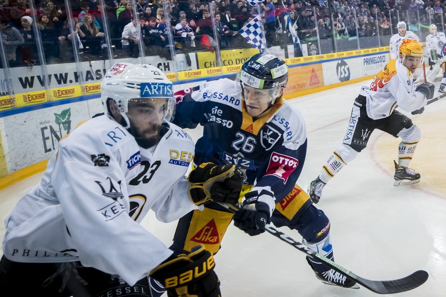 Zugs Reto Suri, Mitte, gegen Luganos Giovanni Morini, links waehrend dem Eishockey-Meisterschaftsspiel der National League zwischen dem EV Zug und dem HC Lugano am Dienstag, den 9. Januar 2018, in der ...