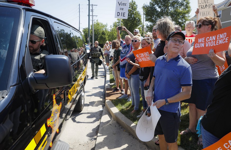 Demonstrators gather while authorities keep them across the street during their protest against the arrival of President Donald Trump outside Miami Valley Hospital after a mass shooting that occurred  ...