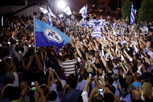 Greek opposition New Democracy conservative party leader Kyriakos Mitsotakis, left, talks to his supporters after win the parliamentary elections at the New Democracy headquarters in Athens, on Sunday ...