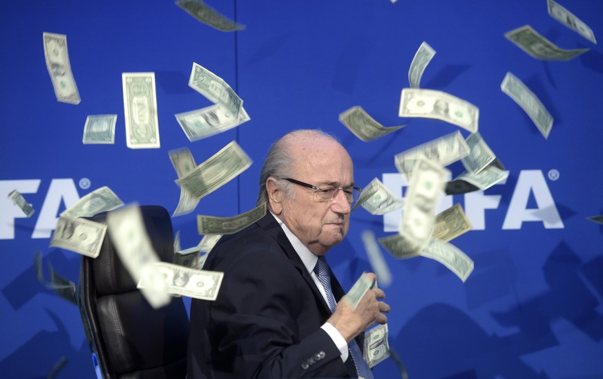 epa09886194 (FILE) In file photo FIFA president Sepp Blatter is photographed while banknotes thrown by British comedian Simon Brodkin hurtle through the air during a press conference following the ext ...