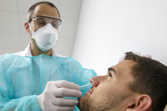 Doctor Julien Salamun collects a sample nasopharyngeal on a person suspected of being infected with the new coronavirus COVID-19, SARS-CoV2, at the University Hospital in Geneva, Switzerland, Tuesday, ...