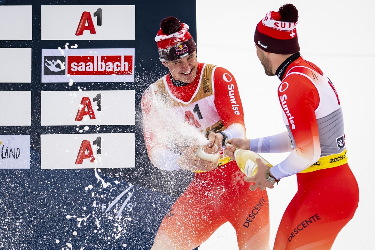 Gold medalist Franjo von Allmen, left, and Bronze medalist Alexis Monney of Switzerland, right, celebrate with champagne during the podium ceremony of the men's Downhill race at the 2025 FIS Alpi ...