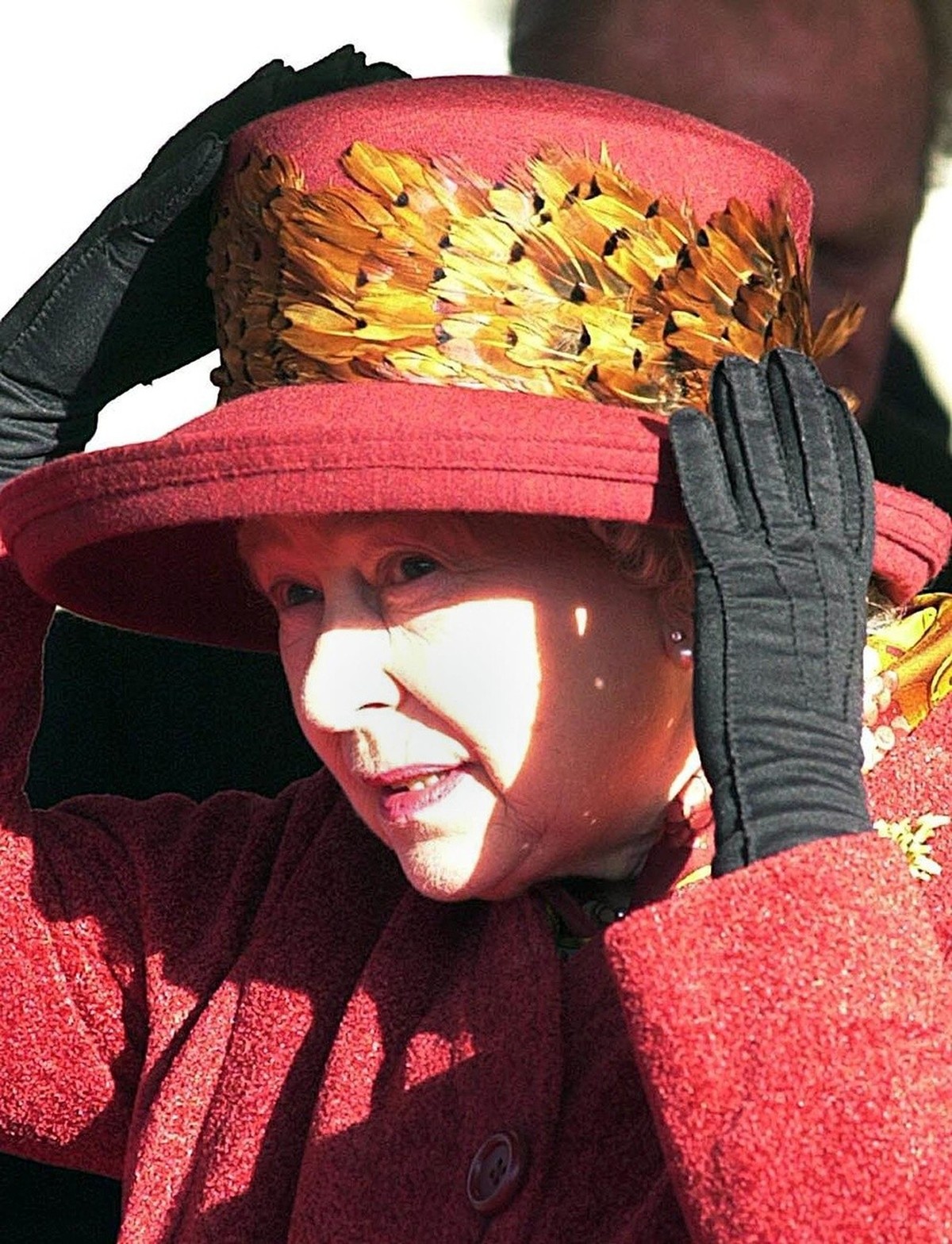16 February 2000 of Britain's Queen Elizabeth II holding onto her hat as she waits for the arrival Queen Margrethe of Denmark at Windsor Castle prior to the start of the Danish monarch's thr ...