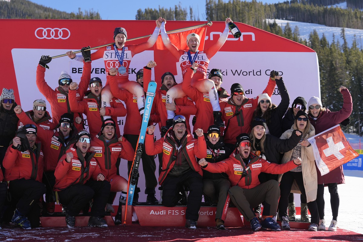 Second place finisher Switzerland's Marco Odermatt, top left, and first place finisher Justin Murisier, top right, celebrate with teammates and coach after a men's World Cup downhill skiing  ...