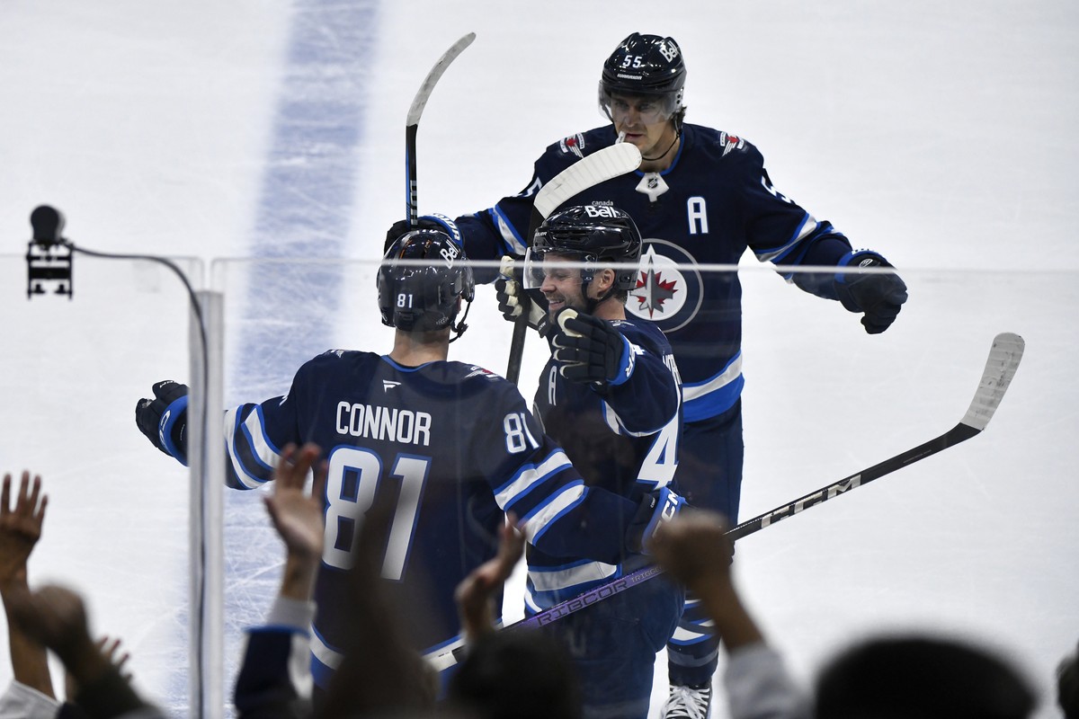Winnipeg Jets' Kyle Connor (81) celebrates after his winning goal against the Minnesota Wild with Josh Morrissey (44) and Mark Scheifele (55) during overtime NHL hockey game action in Winnipeg, M ...