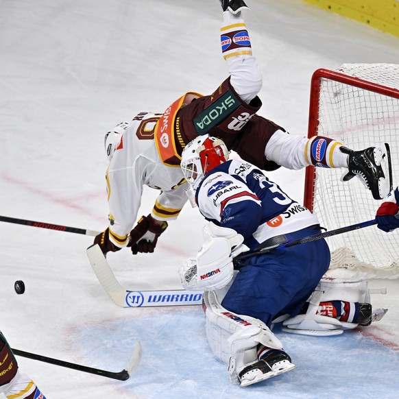 Der Genfer Noah Rod, lin ks, beim Sturzflug ueber den Zuercher Torhueter Simon Hrubec, rechts, beim Eishockeyspiel der National League ZSC Lions gegen Geneve-Servette HC in der Swiss Life Arena in Zue ...