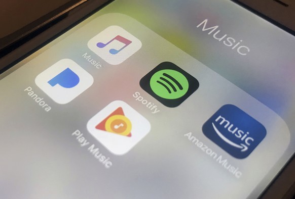 FILE- This Jan. 28, 2018, file photo shows music streaming apps clockwise from top left, Apple, Spotify, Amazon, Pandora and Google on an iPhone in New York. Music-streaming pioneer Spotify will expan ...