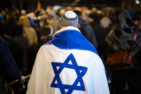 Ein Mann mit einer Israelischen Fahne und einer Kippa protestiert mit anderen gegen Antisemitismus und Rassismus an der Ecke Selnau- und Brandschenkestrasse, am Donnerstag, 7. Maerz 2024 in Zuerich. A ...