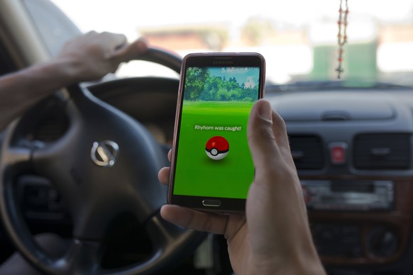 In this Wednesday, July 20, 2016 photo, Egyptian dentist Mark Shehata, 24, uses the &quot;Pokemon Go&quot; mobile phone application while driving in Cairo, Egypt. Abbas Shumman, the deputy sheikh of E ...