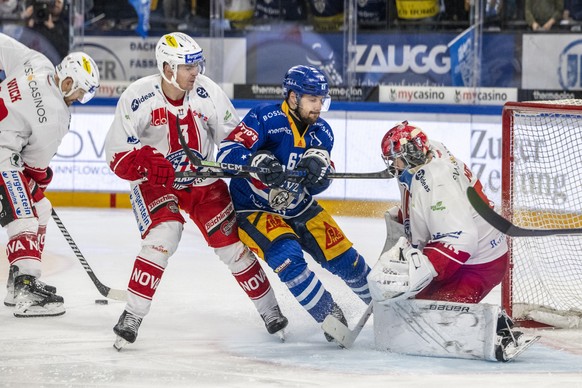 Sven Leuenberger, mitte, von Zug im Spiel gegen Torhueter Robin Meyer, rechts, von Rapperswil beim dem Eishockey Meisterschaftsspiel der National League zwischen dem EV Zug und dem Rapperswil Lakers a ...