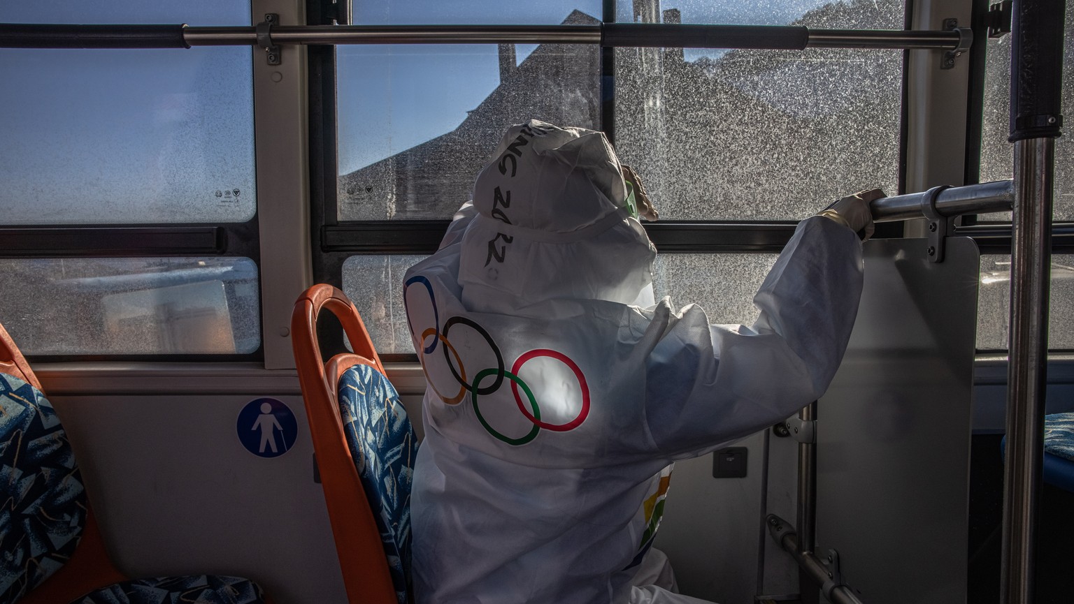 epa09716426 A person wearing protective gear with Olympic rings on it, rides a bus inside the Olympic COVID-19 &#039;bubble?, near the venues for Beijing 2022 Winter Olympics, in Zhangjiakou, China, 2 ...