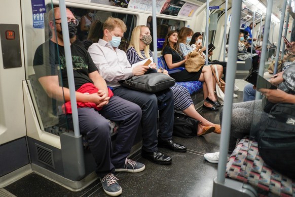 FILE - In this file photo dated Monday, July 19, 2021, people sit on an Underground train in London, as face masks and social distancing rules are relaxed along with limits on the number of people att ...