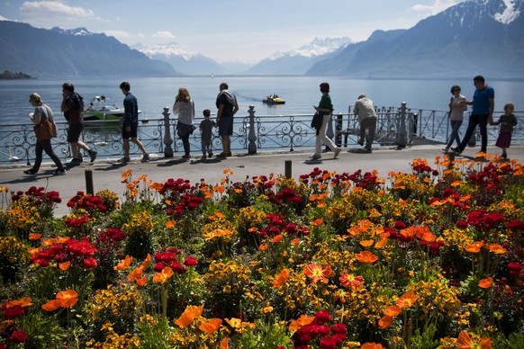 Des personnes regardent le lac Leman et les montagnes en profitant du soleil et des temperatures printanieres ce samedi 7 mai 2016 a Vevey. (KEYSTONE/Jean-Christophe Bott)
