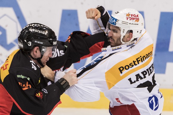 SC Bern Verteidiger Justin Krueger, links, und HC Lugano Stuermer Maxim Lapierre inszenieren einen Boxkampf, die Linienrichter Balazs Kovacs, links, und Franco Castelli ueberwachen, im Eishockey Meist ...