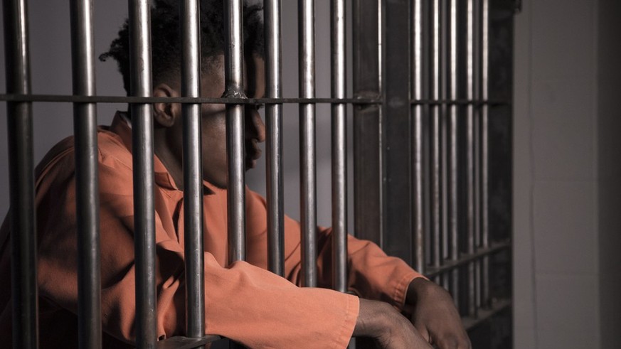 Ein Häftling blickt aus seiner Gefängniszelle. An inmate in his prison cell.