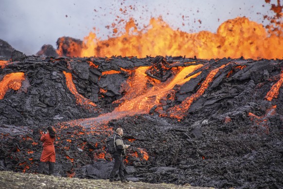 People look at the lava flowing on Fagradalsfjall volcano in Iceland on Wednesday Aug. 3, 2022, which is located 32 kilometers (20 miles) southwest of the capital of Reykjavik and close to the interna ...