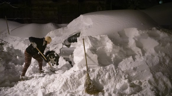 Eine Frau befreit ihr Auto vom Schnee nach den Rekordschneemengen der vergangenen Tage, am Sonntag, 17. Januar 2021, in Valens. (KEYSTONE/Gian Ehrenzeller)