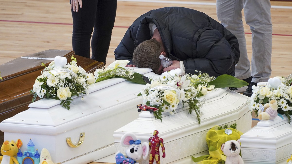 A relative cries on the coffin of one of the victims of last Sunday's shipwreck at the local sports hall in Crotone, southern Italy, Wednesday, March 1, 2023. At least 67 people, including 14 min ...