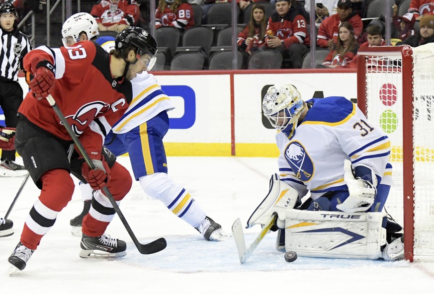 Buffalo Sabres goaltender Dustin Tokarski (31) deflects the puck on a shot by New Jersey Devils center Nico Hischier (13) during the first period of an NHL hockey game Saturday, Oct. 23, 2021, in Newa ...