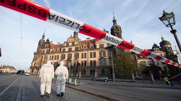 25.11.2019, Sachsen, Dresden: Zwei Mitarbeiter der Spurensicherung stehen vor dem Residenzschloss mit dem Grünen Gewölbe hinter einem Absperrband. In Dresdens Schatzkammer Grünes Gewölbe ist am frühen ...