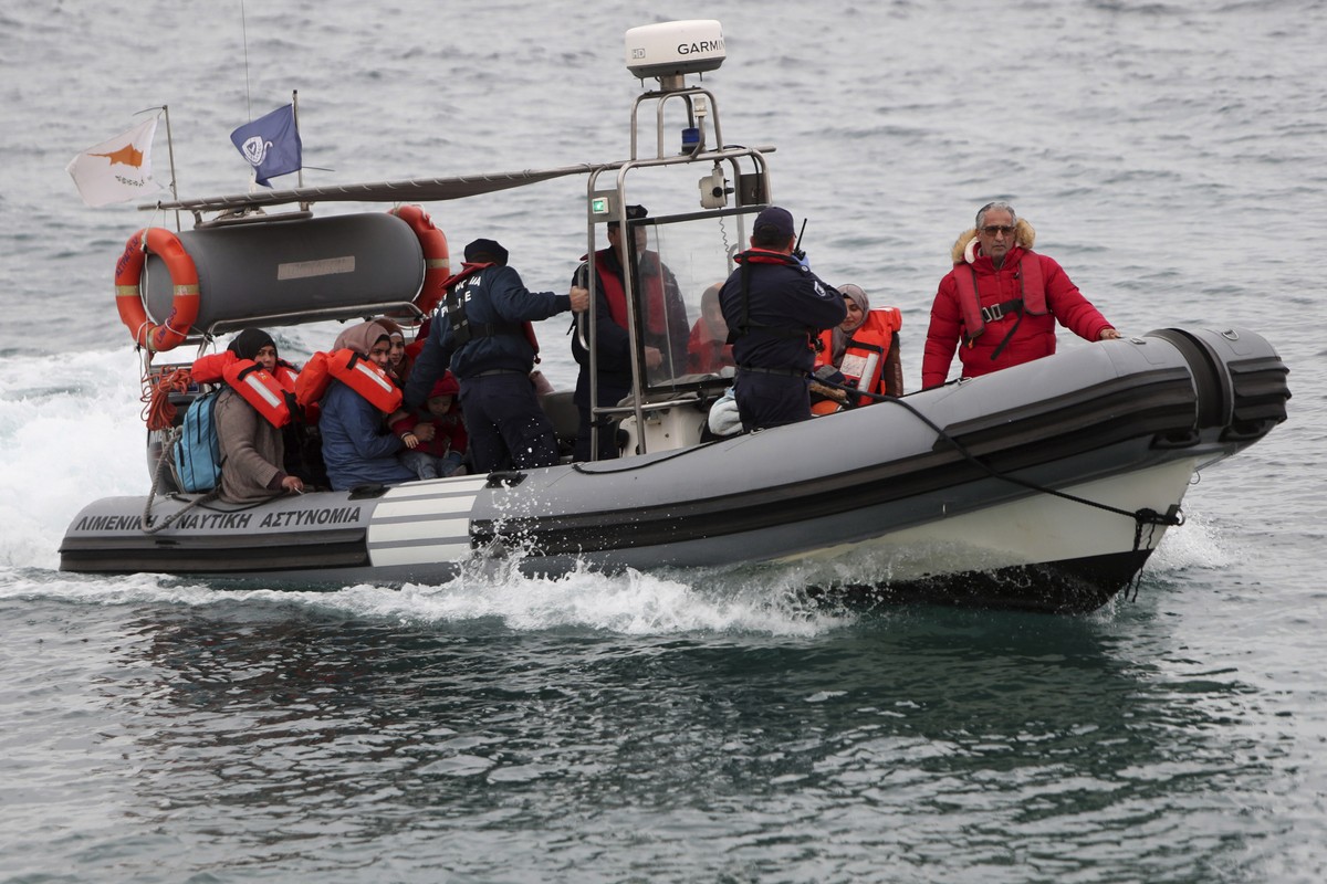 FILE - Migrants sit on a Cyprus marine police boat as they are safely brought to a harbor after being rescued from their own vessel off the Mediterranean island nation's southeastern coast, of Pr ...