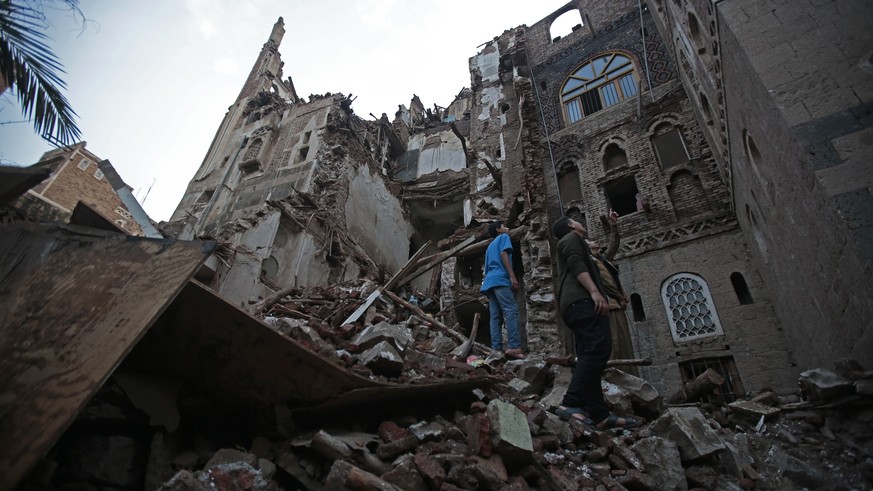 Zwei Personen schauen die kollabierten Häuserzeilen an. Sanaa, 10. August 2022.