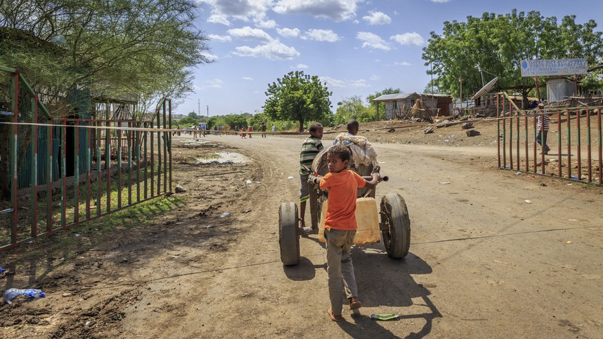 In this photo taken Wednesday, June 3, 2015, local children push a cart of water for sale to Sudanese, in Metema, in northwestern Ethiopia next to the border with Sudan. The town is a center for a boo ...