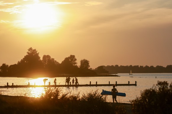 epa12294176 As a heat wave extends into northern Europe, a family enjoys the sunset at a beach on Versemeer lake, near Goes, the Netherlands, 11 August 2025. EPA/OLIVIER HOSLET