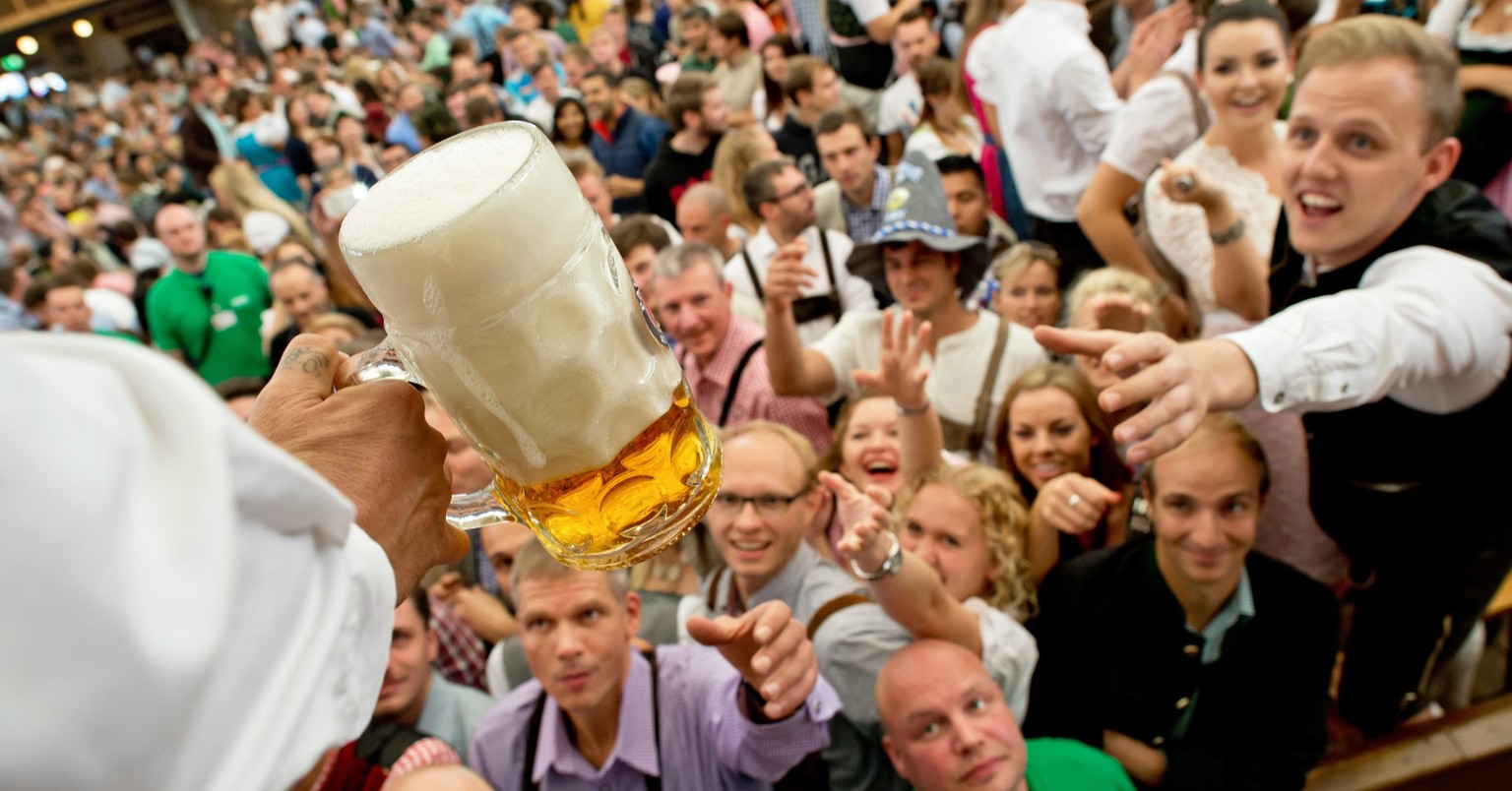 epa04938169 Visitors reach out for the first beer mugs handed out in a beer tent at the 182nd Oktoberfest in Munich, Germany, 19 September 2015. Oktoberfest, Germany's annual 16-day extravaganza  ...