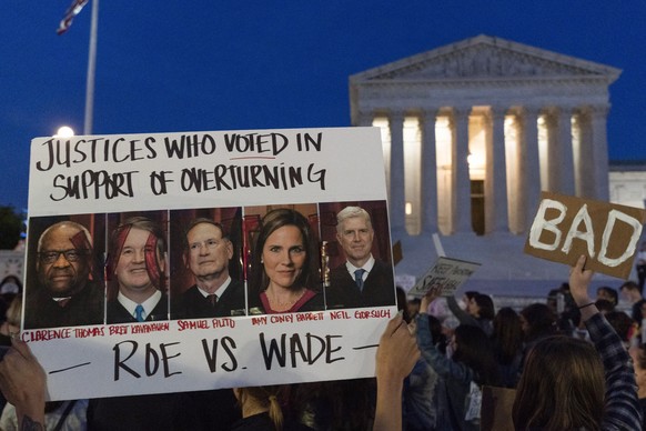 FILE - Nikki Tran of Washington, holds up a sign with pictures of Supreme Court Justices Thomas, Kavanaugh, Samuel Alito, Amy Coney Barrett, and Neil Gorsuch, as demonstrators protest outside of the U ...