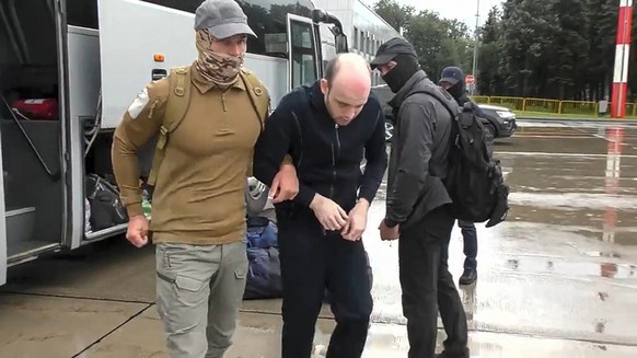 In this image made from video provided by Russian Federal Security Service via RTR on Thursday, Aug. 1, 2024, Germanys Rico Krieger, center, and a Russian Federal Security Service agent, left, leave a ...