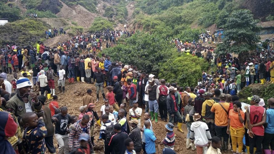 People gather at the scene of a gold mine collapse near the town of Kamituga, South Kivu province, in eastern Congo Friday, Sept. 11, 2020. More than 50 people are dead after landslides collapsed thre ...