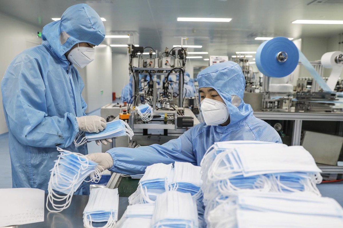 epa08391785 Workers wearing protective suits and face masks produce masks at a factory of the Naton Technology Group in Beijing, China, 29 April 2020, amid the ongoing coronavirus COVID-19 pandemic. E ...
