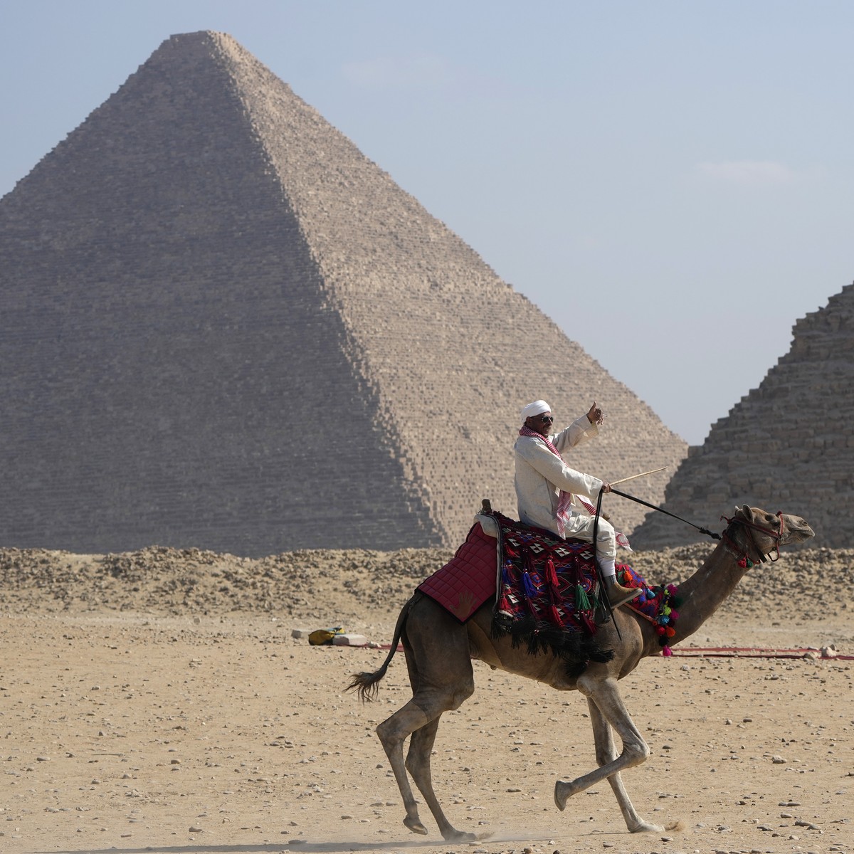 A tourist guide rides a camel at the historical site of Giza Pyramids, on the outskirts of Cairo, Egypt, Tuesday, Oct. 29, 2024. (AP Photo/Amr Nabil)